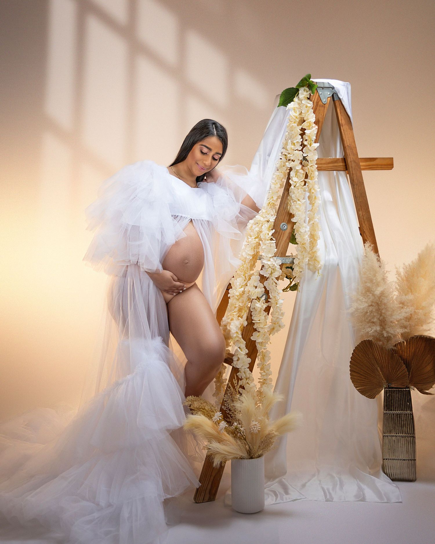 Ethereal maternity portrait with large white angel wings and reflective water effect.