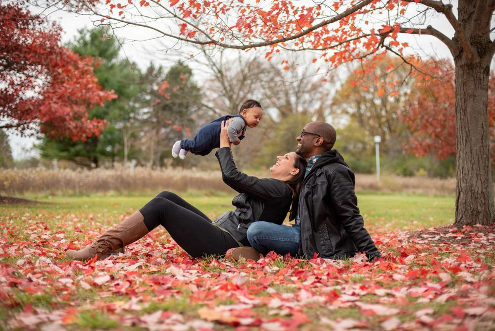 Couple sitting in the leaves with their baby