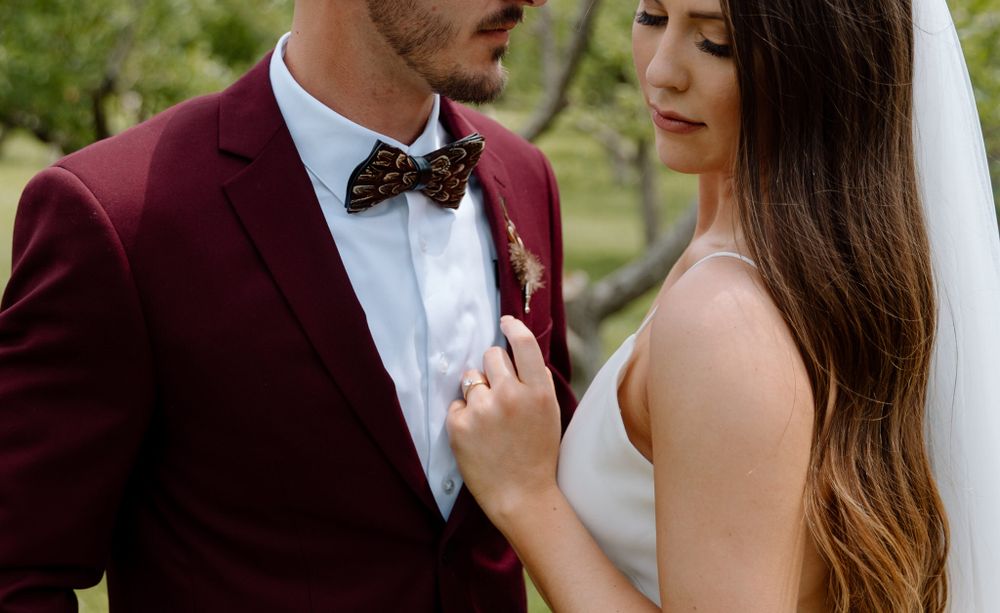Romantic wedding portrait featuring burgundy suit and white dress details.