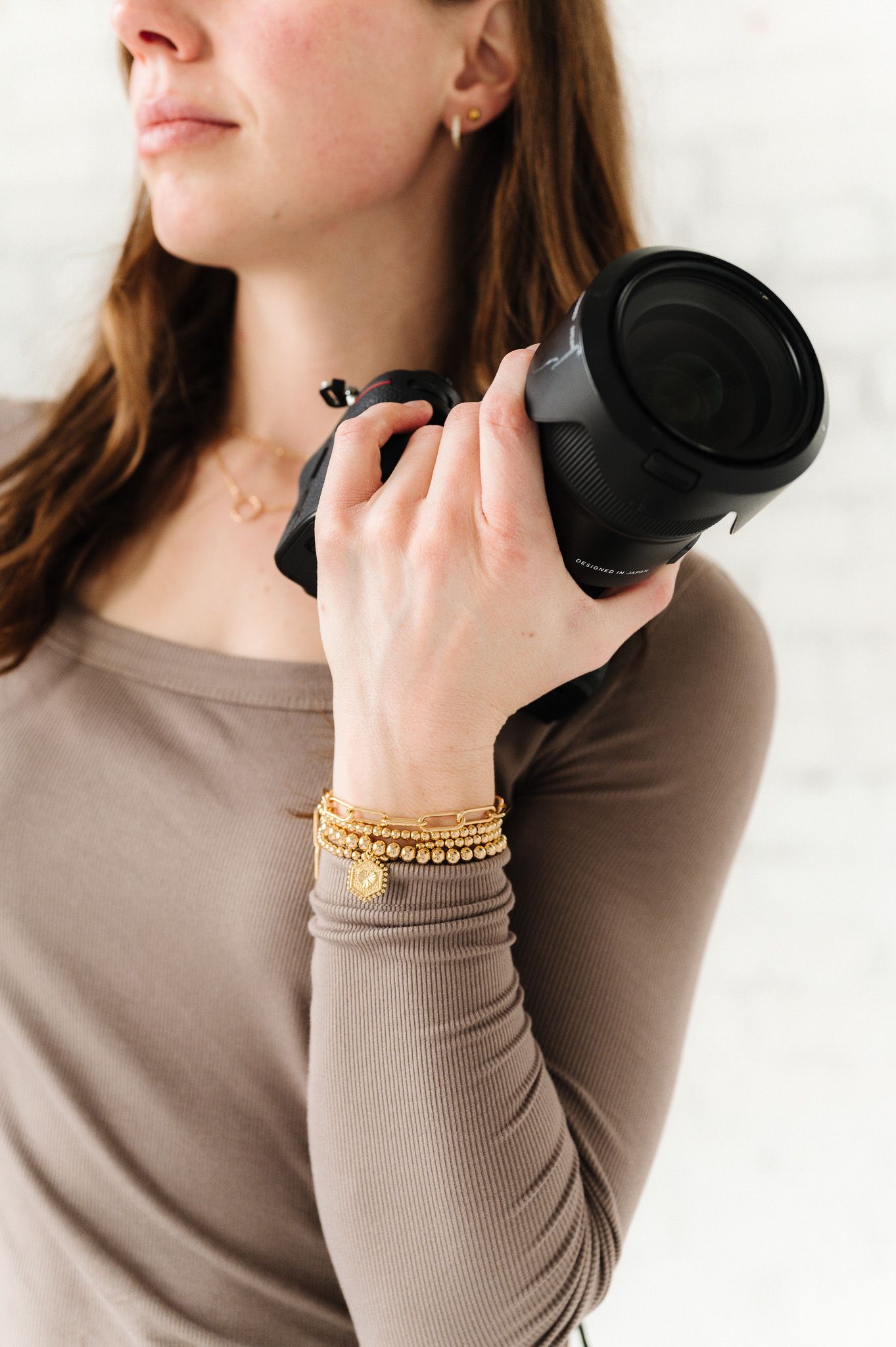 Close-up shots of hands wearing gold beaded bracelets while holding camera equipment.