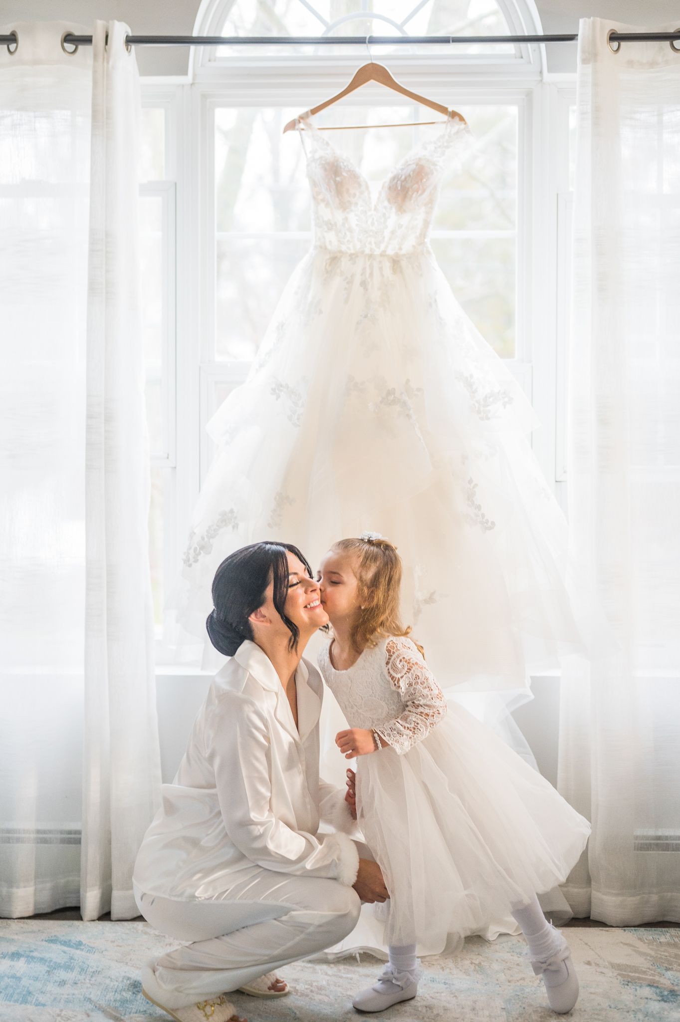 Touching moment as the flower girl gives the bride a kiss on the cheek.