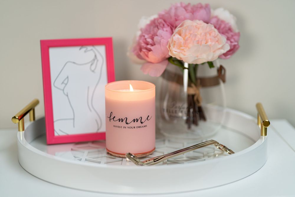 Elegant pink candle display with flowers and minimalist artwork on white tray.