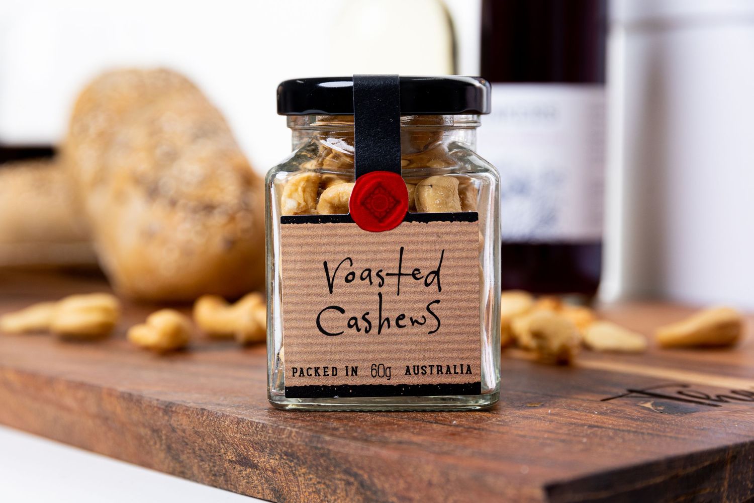 Glass jar of spices labeled 'Roasted Cashews' on wooden cutting board.