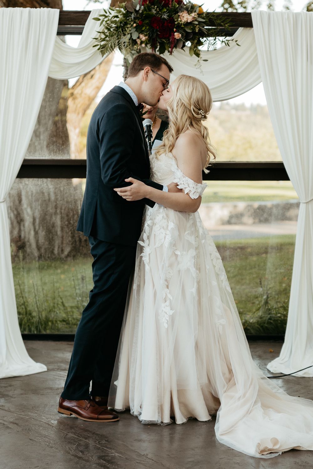 A romantic wedding moment under a draped canopy with floral decor and white curtains.