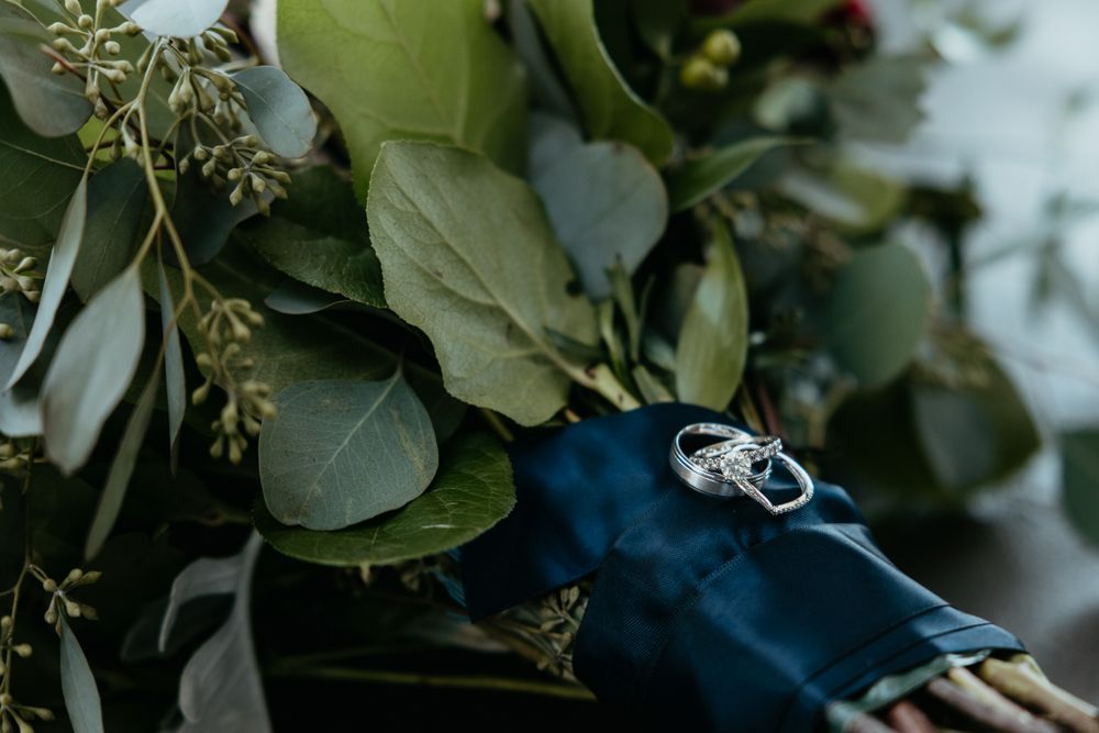 Wedding rings nestled among green eucalyptus leaves and foliage.