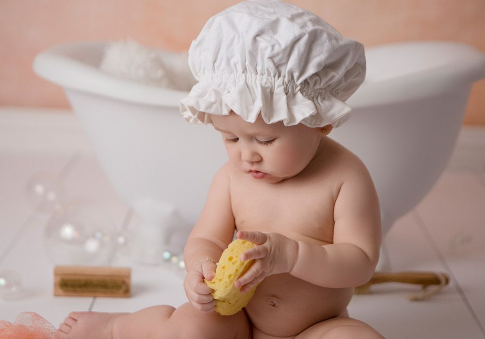 Adorable bath time scene with a white cap and yellow sponge against a peachy background.