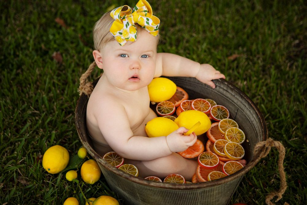 Creative citrus-themed photo setup with lemons and oranges in a rustic metal tub.