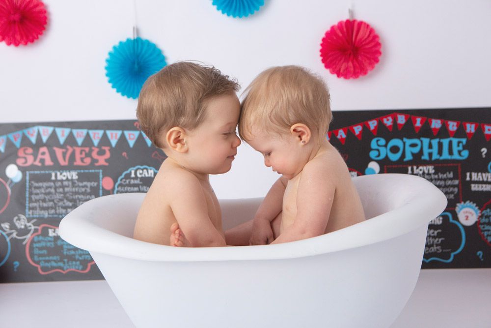 Heartwarming bath time moment with two little ones sharing a white tub.