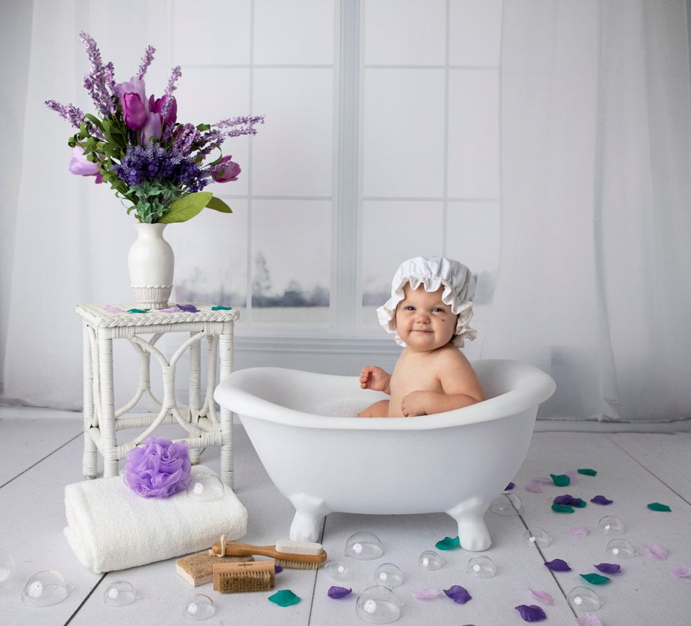 Spa-like bathroom scene with white tub, purple flowers, and scattered petals on floor.