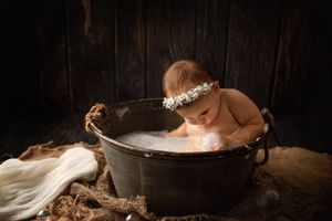 Dreamy bath scene with bubbles in vintage metal tub against dark wooden backdrop.