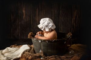 Vintage bath scene with white bonnet and fabric against rustic wooden wall.