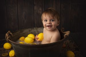 Joyful bath time scene with bright lemons in vintage metal washtub.