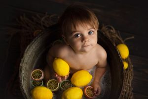 Rustic bath setup with bright yellow lemons and vintage metal tub against dark backdrop.
