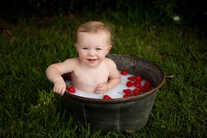 Bath time in metal tub outdoors with floating red rose petals.