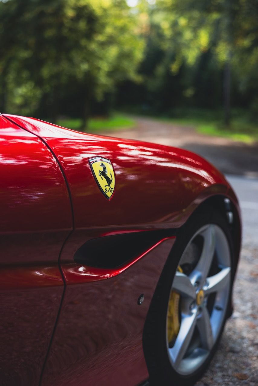 Close up der Felge und des seitlichen Ferrari Emblems eines roten Ferrari Portofino.