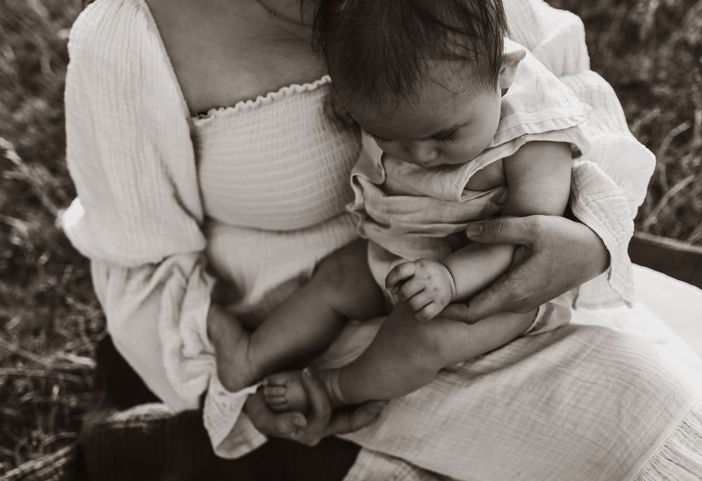 An intimate black and white portrait of a baby being cradled in someone's arms.