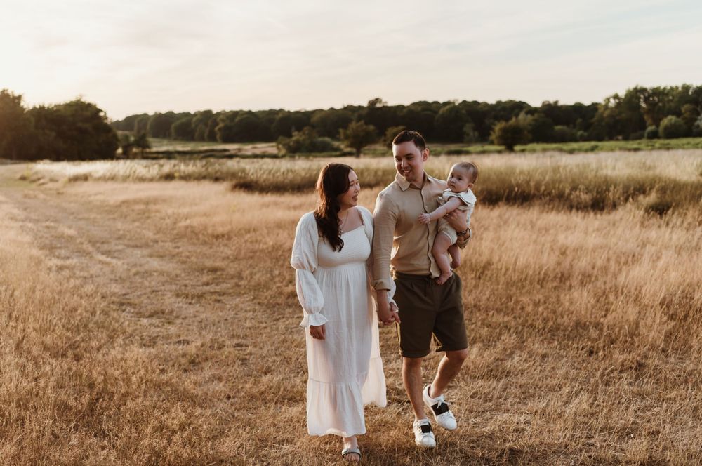 A family shares a joyful moment together in a sun-lit field during golden hour.