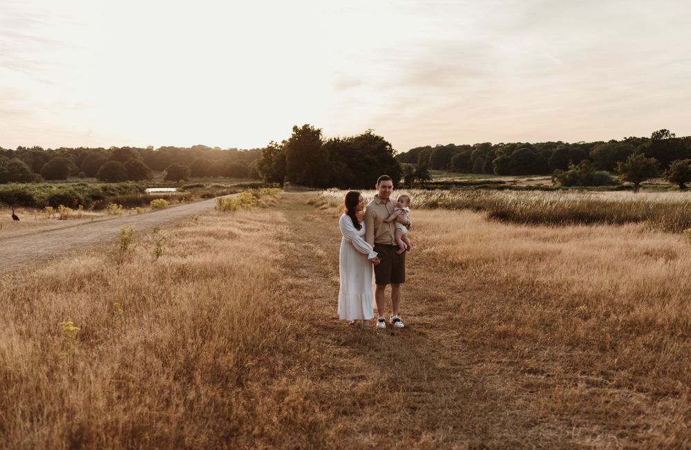 A family stands together in a serene field bathed in warm evening light.