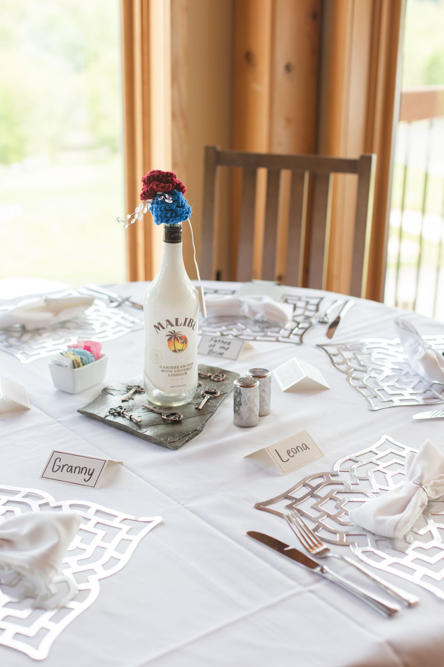 Elegant white wedding reception table setting with lace tablecloth and place cards.