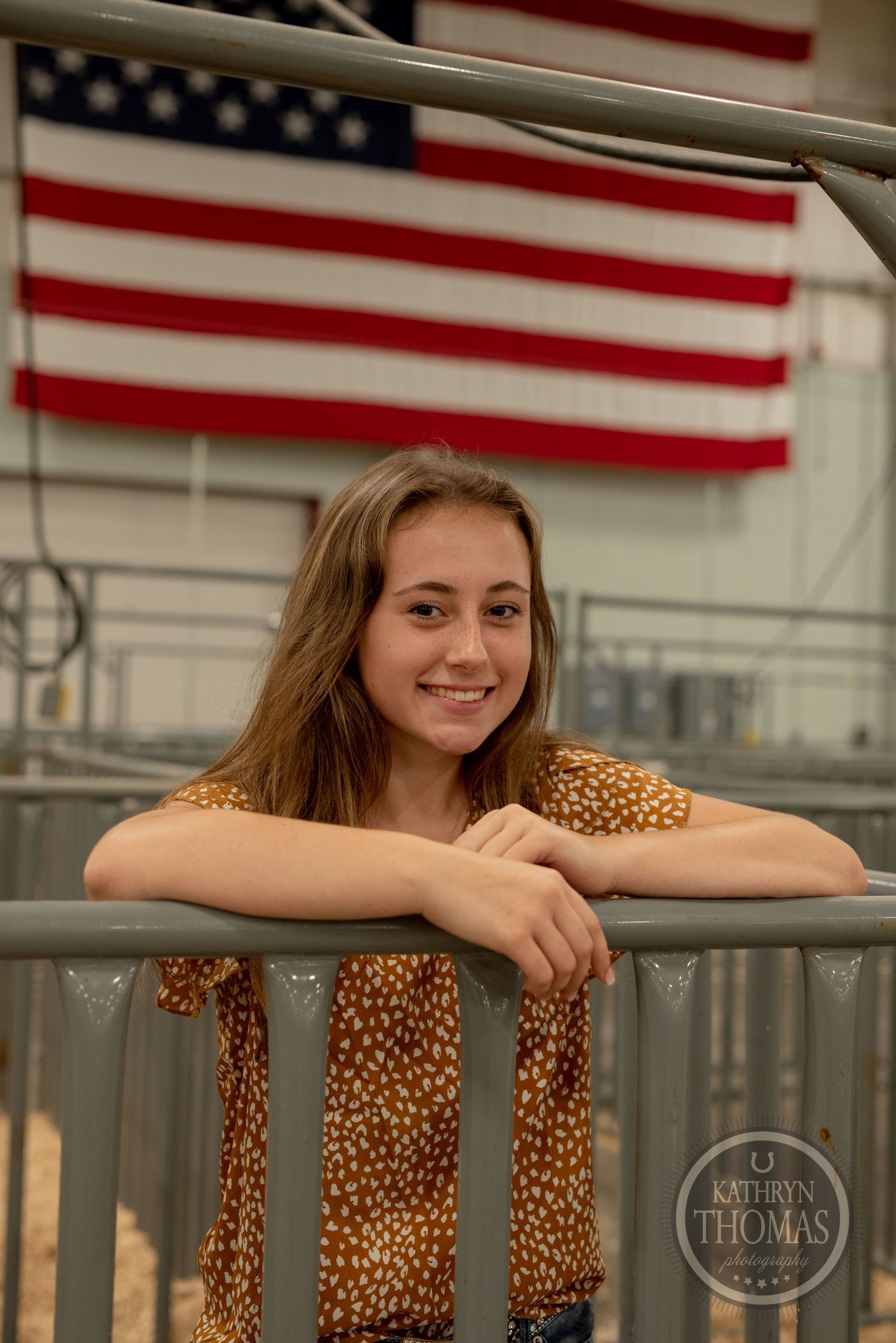 American flag hangs prominently in livestock barn with metal pens and gates.