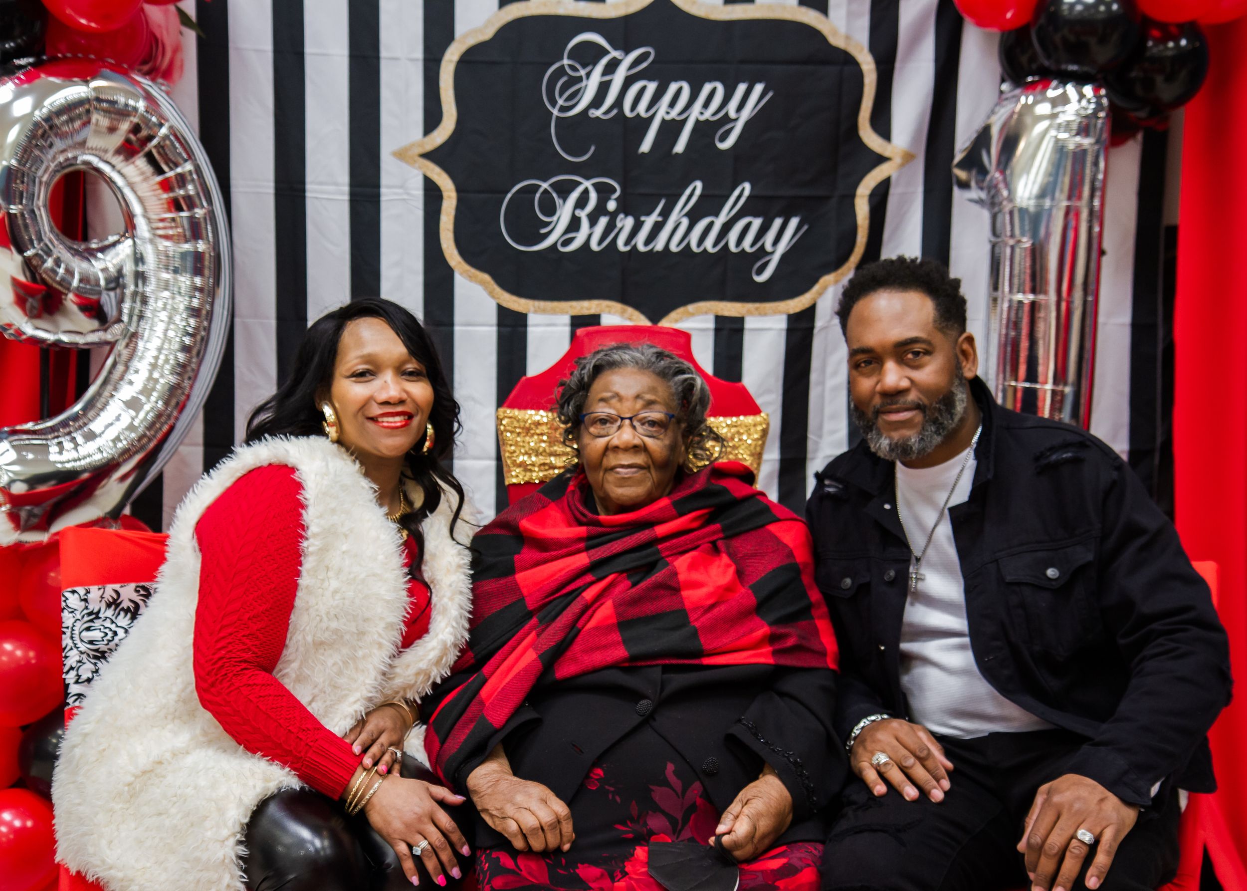 Birthday celebration with black and white striped backdrop and red balloon decorations.