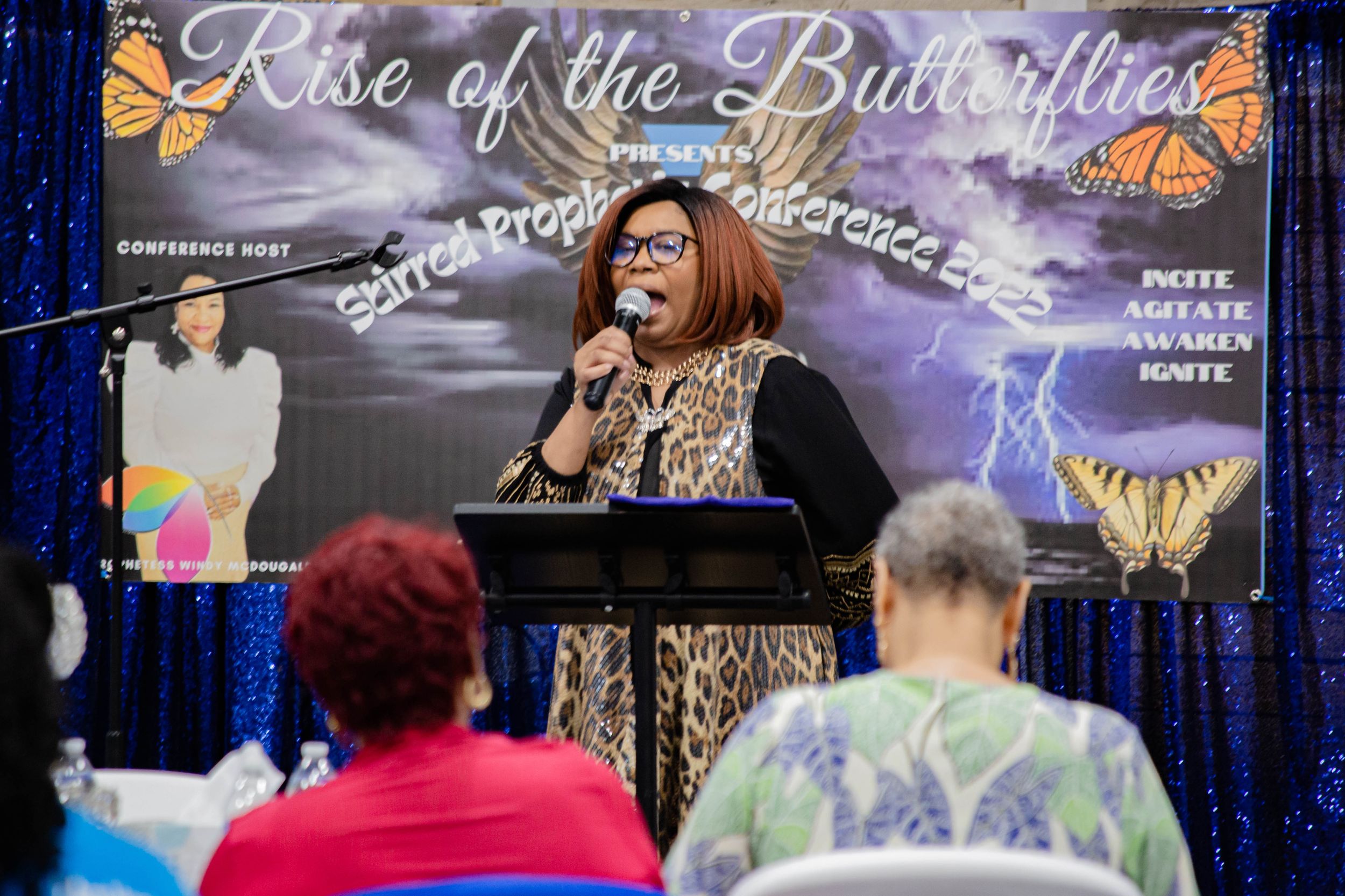 Singer performing at Rise of the Butterflies event with butterfly-themed backdrop.