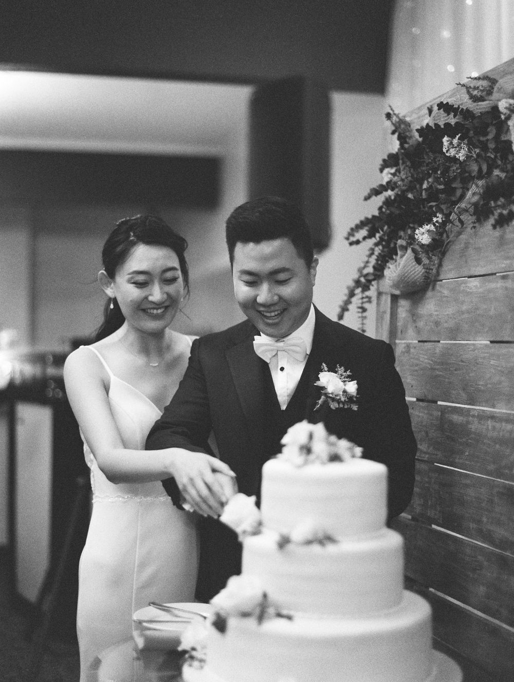 A couple cuts their elegant white wedding cake together at their reception.