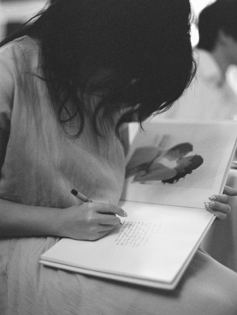 Black and white photo of person signing guestbook at wedding reception.