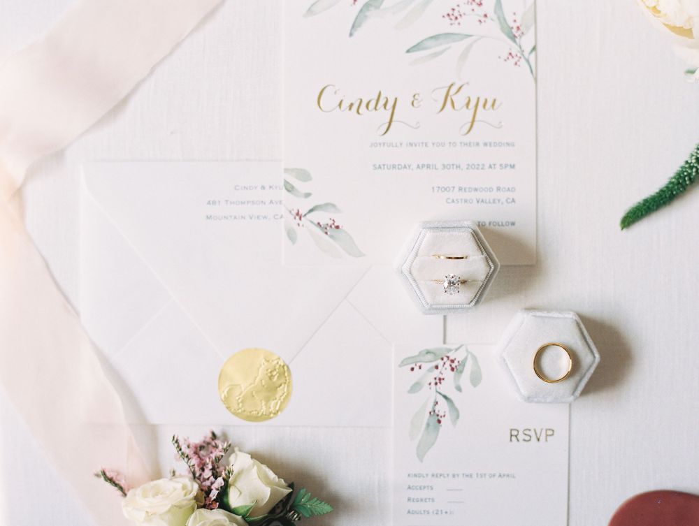 Wedding invitation suite with hexagonal ring boxes, floral details and elegant typography.