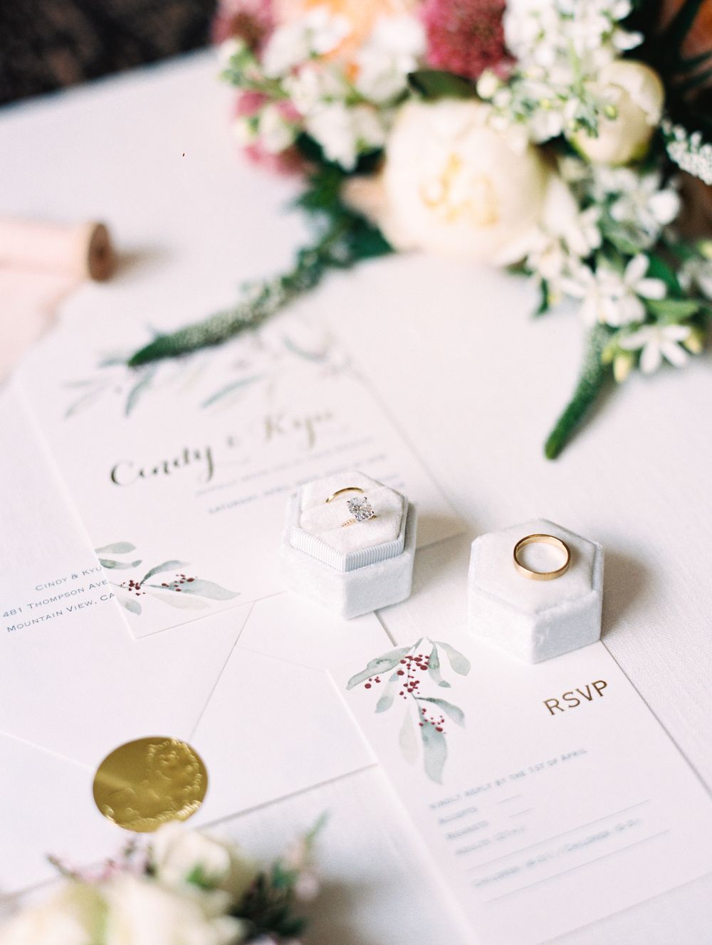 Elegant wedding stationery with hexagonal ring boxes and fresh floral arrangements.