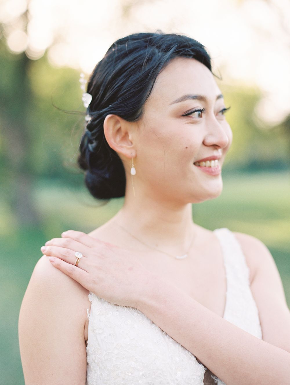Wedding portrait showing elegant updo hairstyle, earrings and white lace dress.