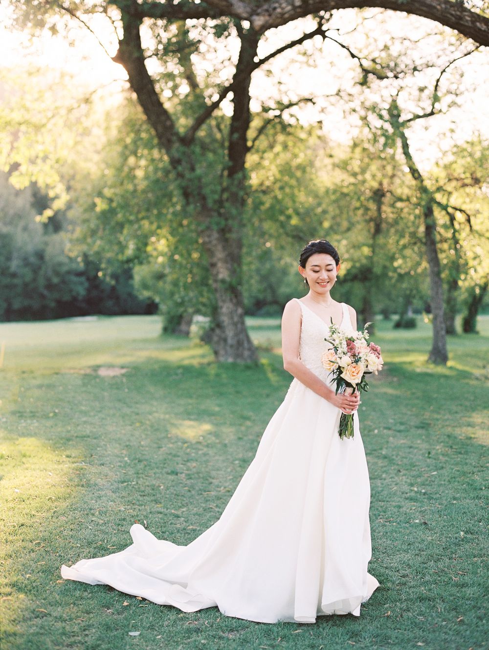 Romantic outdoor bridal portrait with flowing white gown in golden afternoon light.