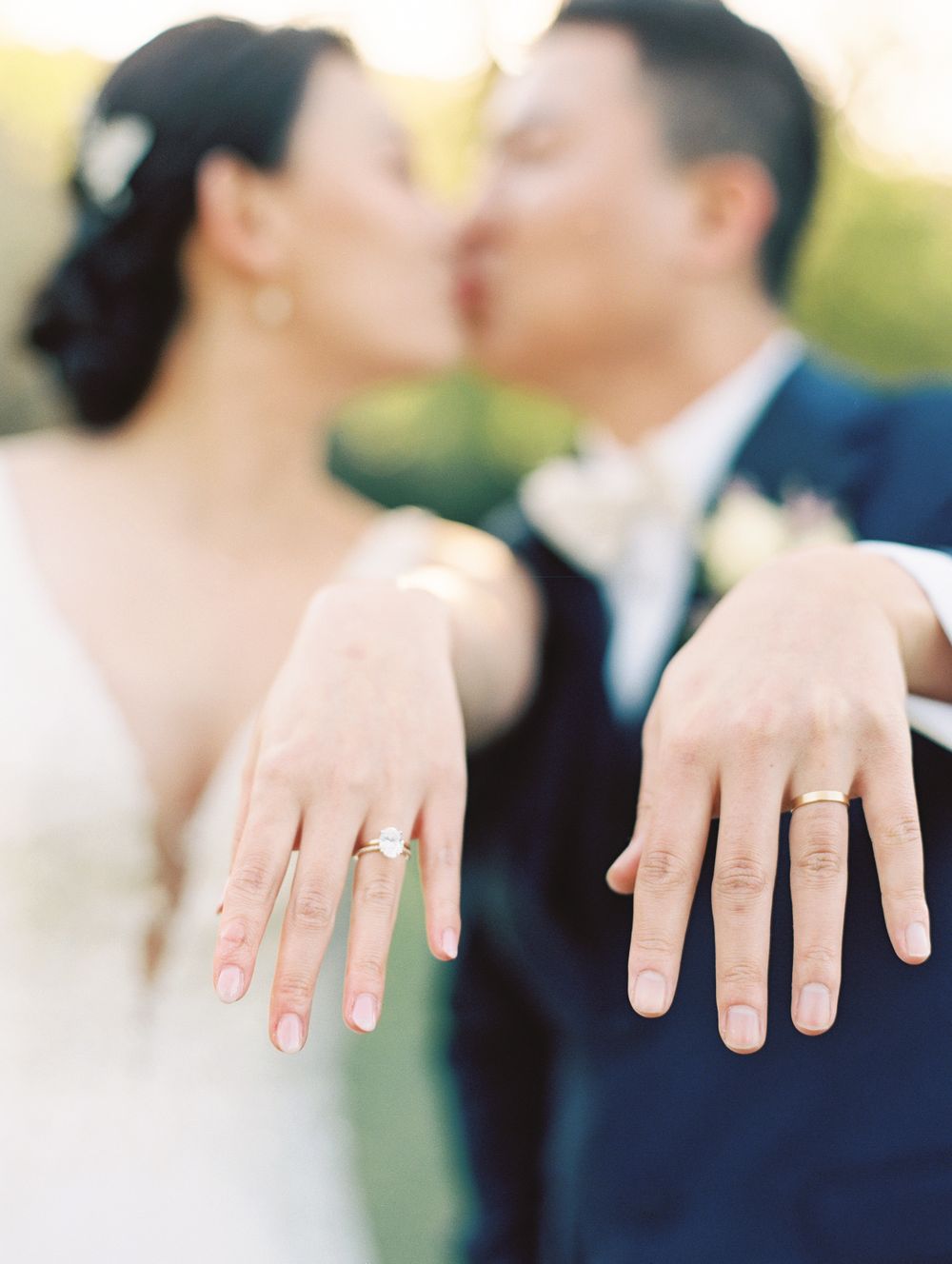 Close up of wedding rings displayed on hands with soft focus background.