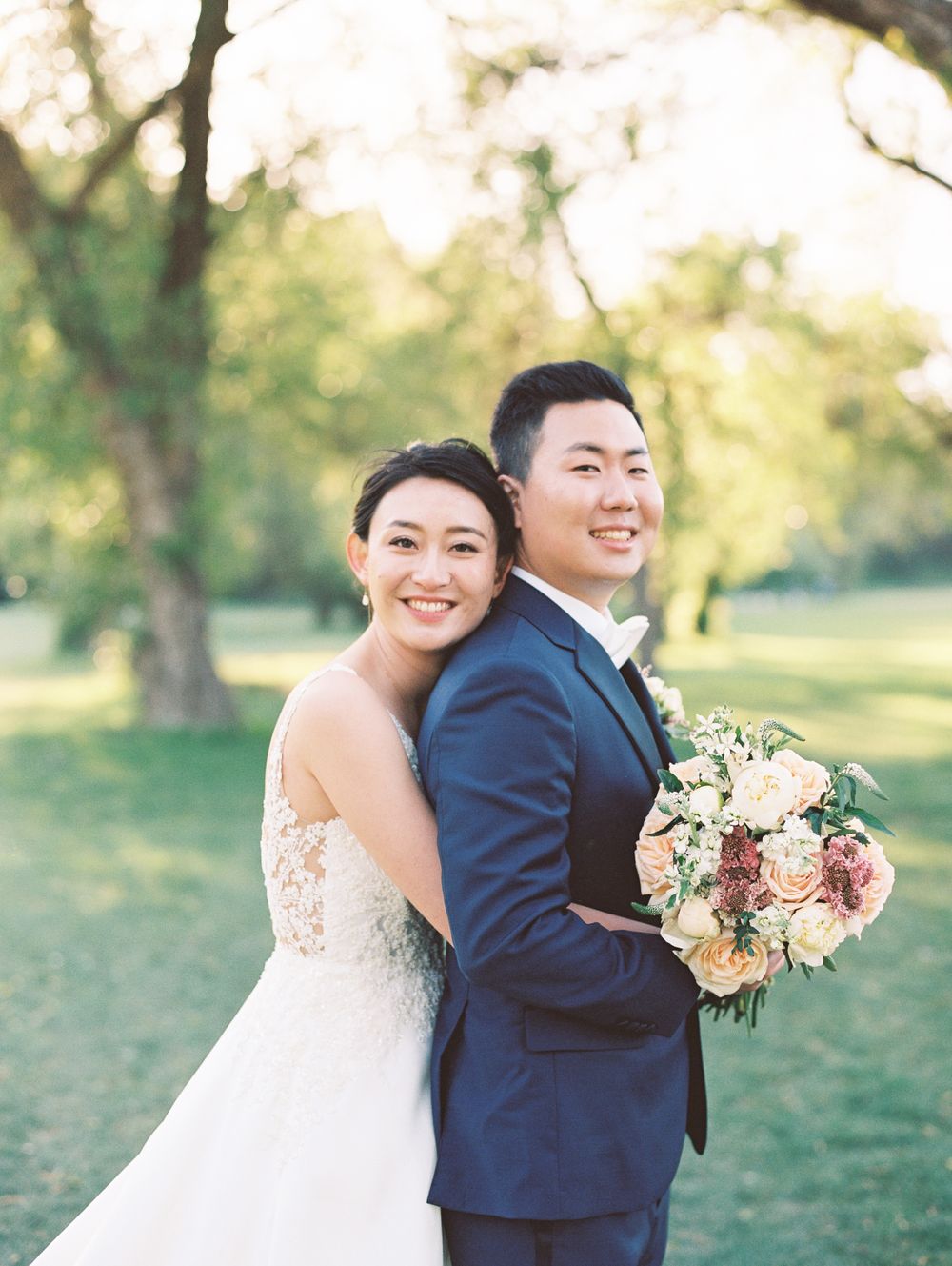 Romantic outdoor wedding portrait with lush greenery and soft lighting.