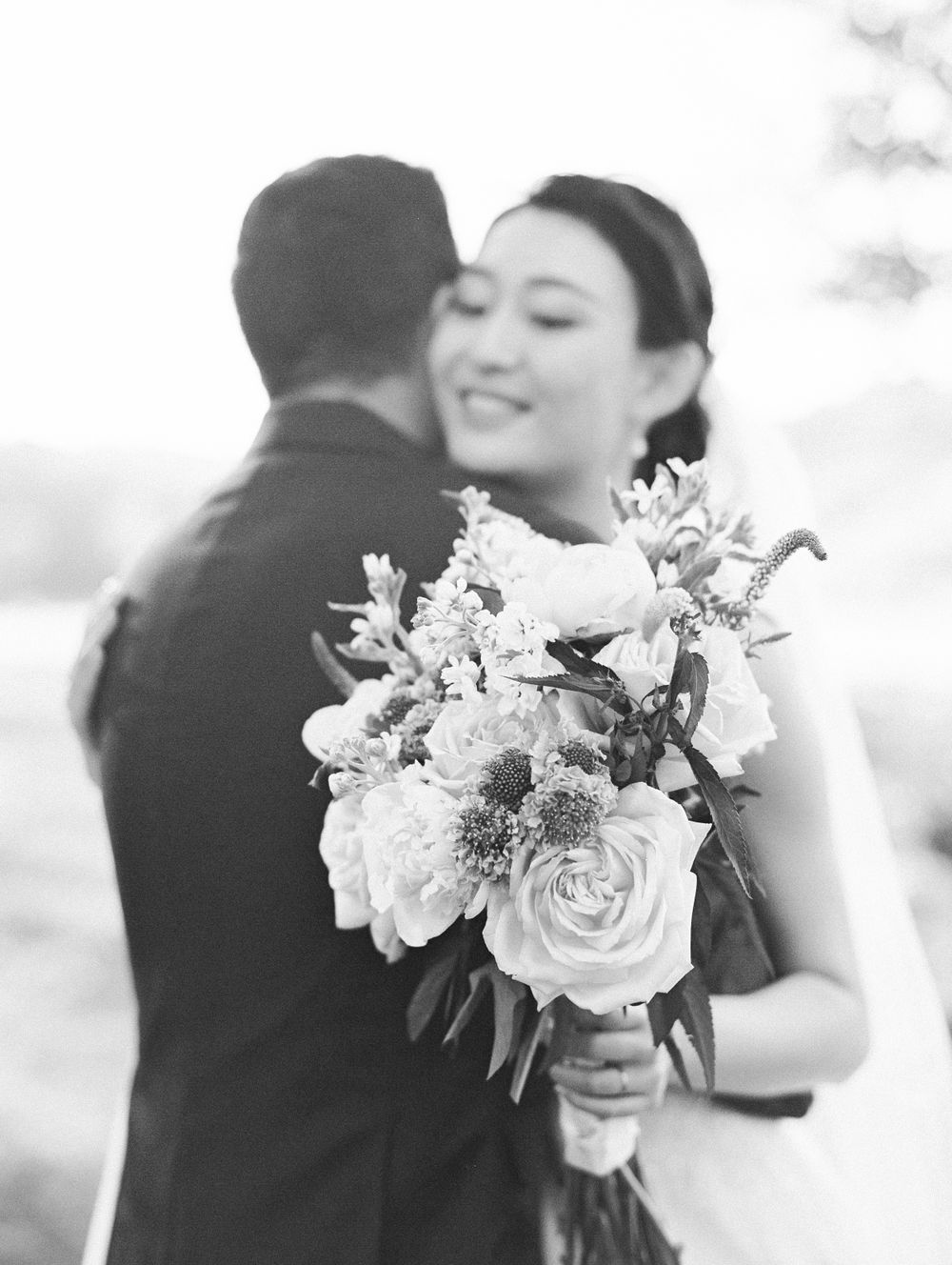 An elegant bridal bouquet of white roses and mixed flowers in black and white photography.