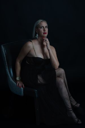 Moody boudoir photoshoot series in dark setting with dramatic lighting and chair.