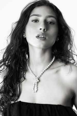 Black and white artistic portrait series showing dark hair and pearl necklace against white background.