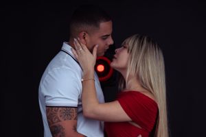 Intimate couple portrait in dark setting with red accent lighting.