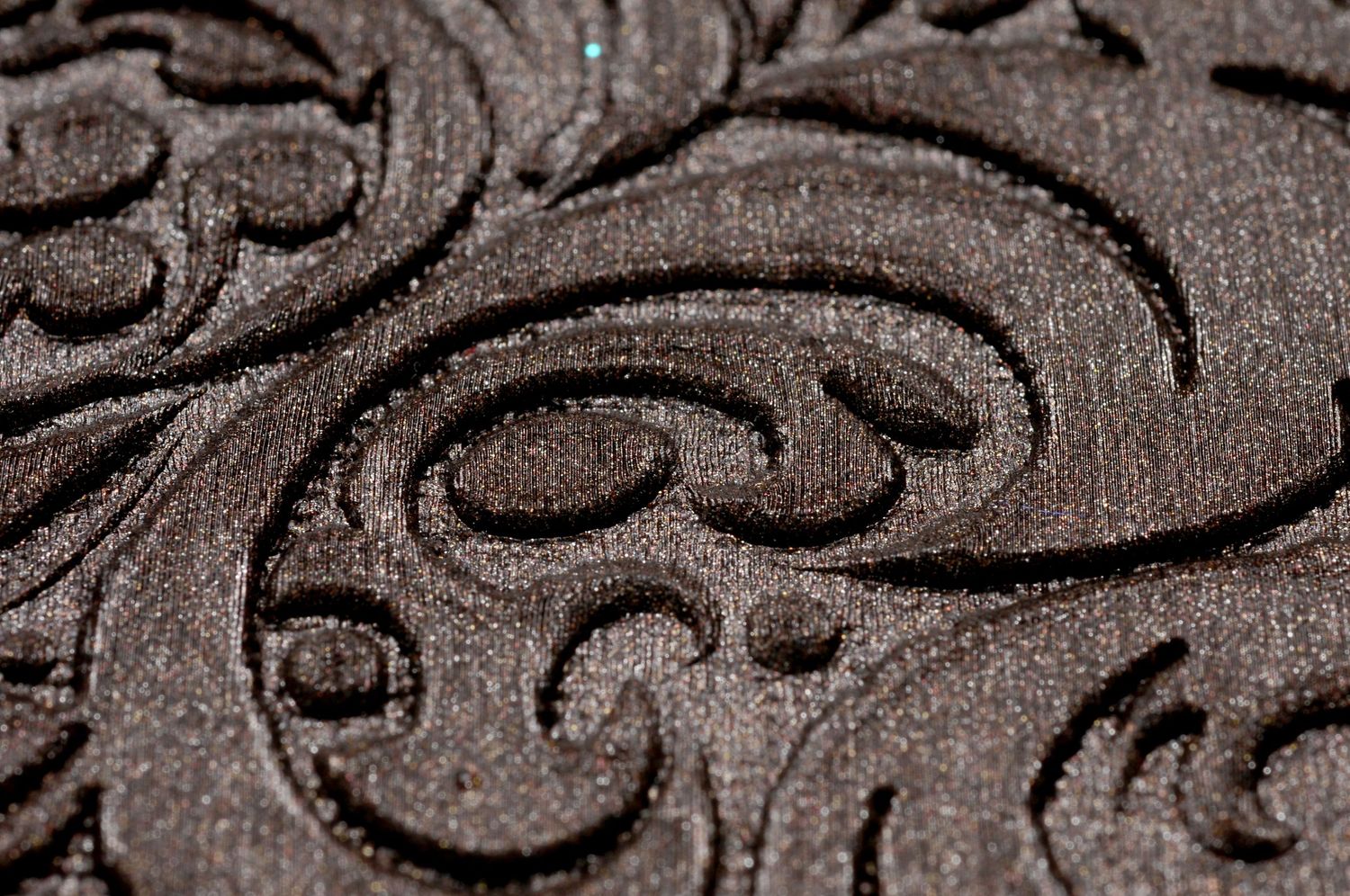 Close-up macro shot of an elegant brown floral damask pattern with embossed swirling designs carved into fabric.