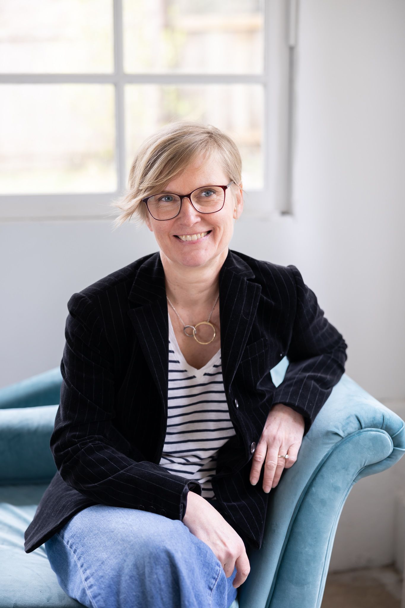 woman siting on blue couch for headshots in woodinville, WA