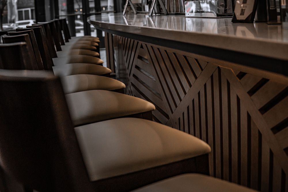 Row of cushioned bar stools along a decorative wooden bar panel.