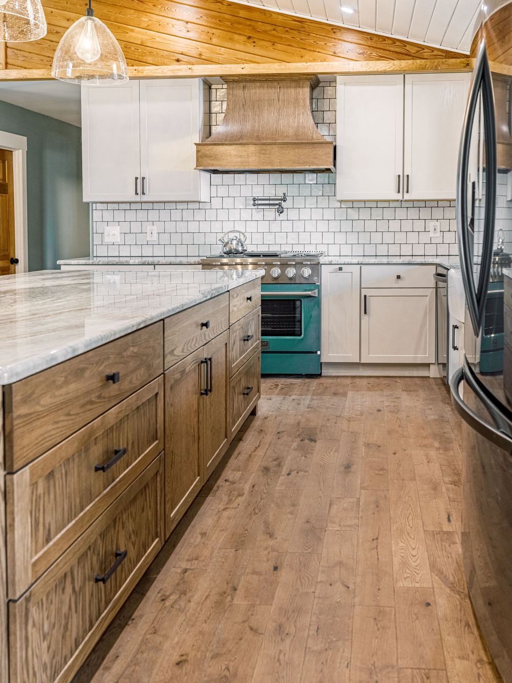 Farmhouse kitchen featuring white cabinets, subway tile, and wooden lower cabinets.
