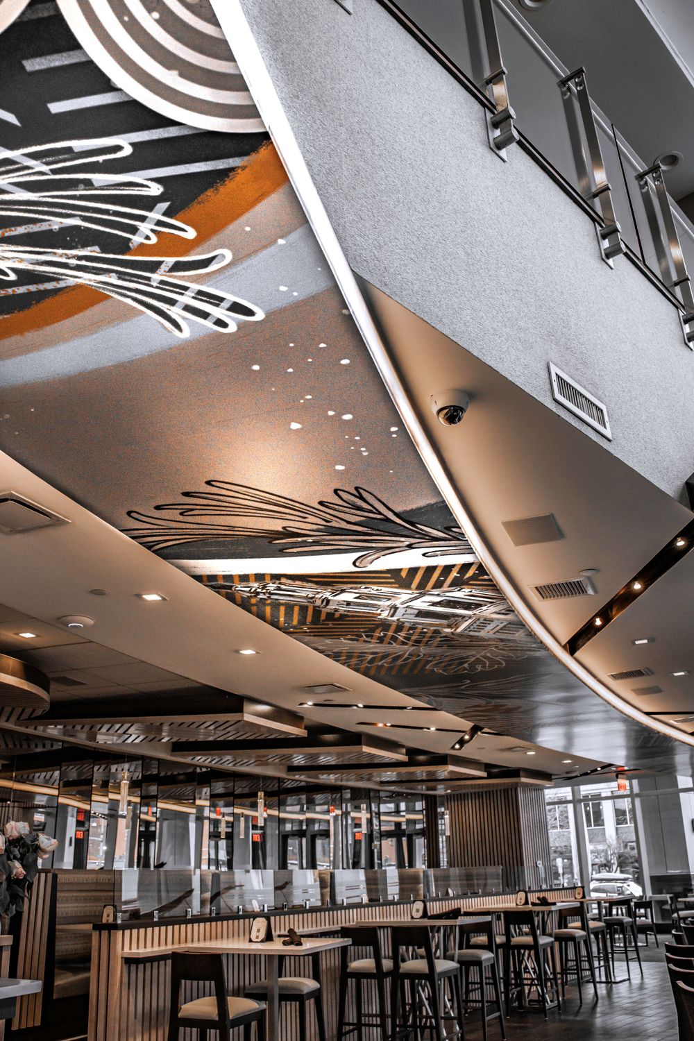 Contemporary restaurant ceiling with artistic patterns and modern lighting fixtures.