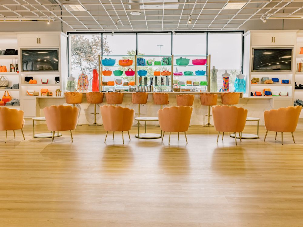 Modern dining area with orange accent chairs and vibrant kitchenware wall display.
