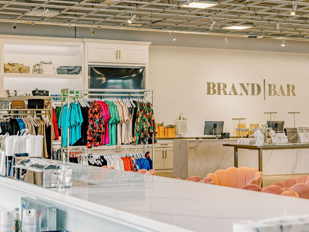 Modern retail store interior with colorful clothing displays and brand bar signage on white walls.