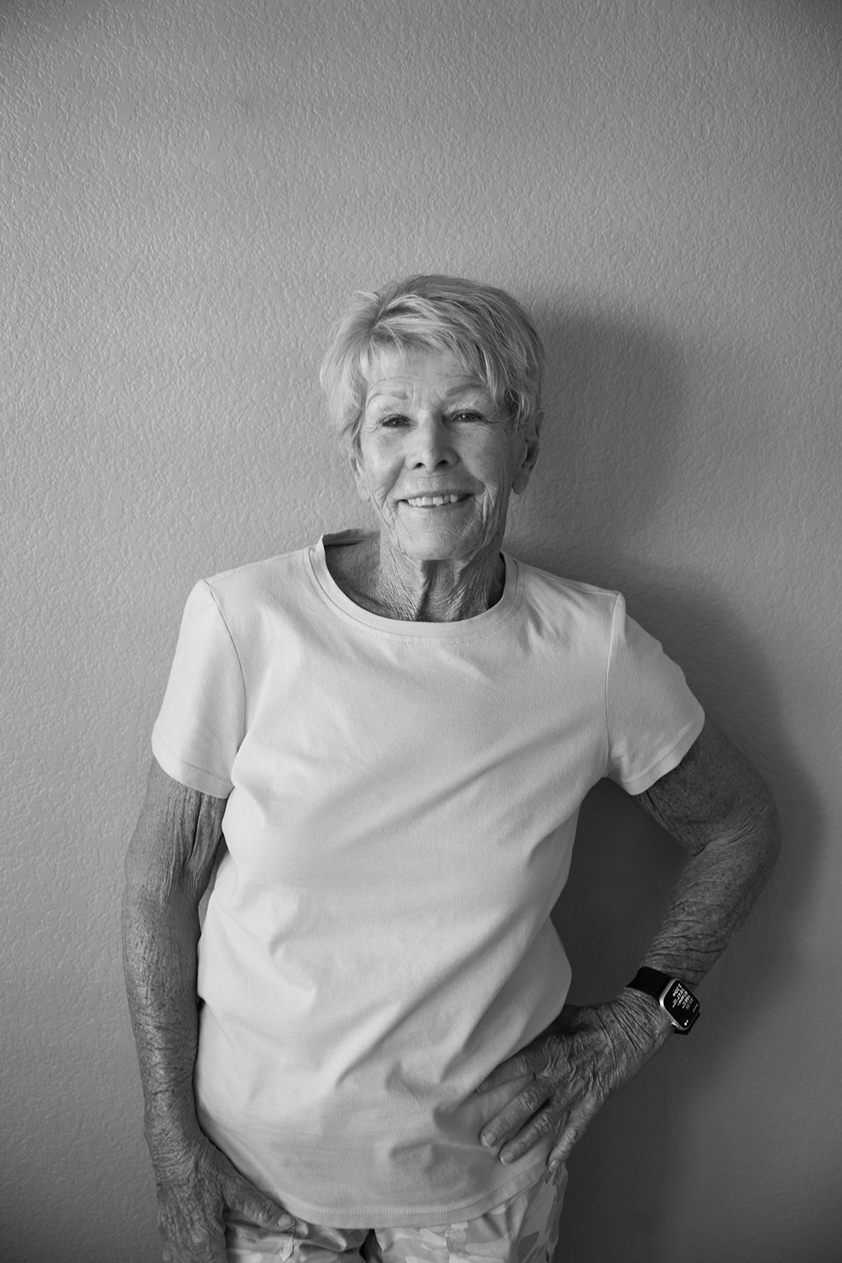 Black and white series of playful poses against a wall wearing white t-shirt.