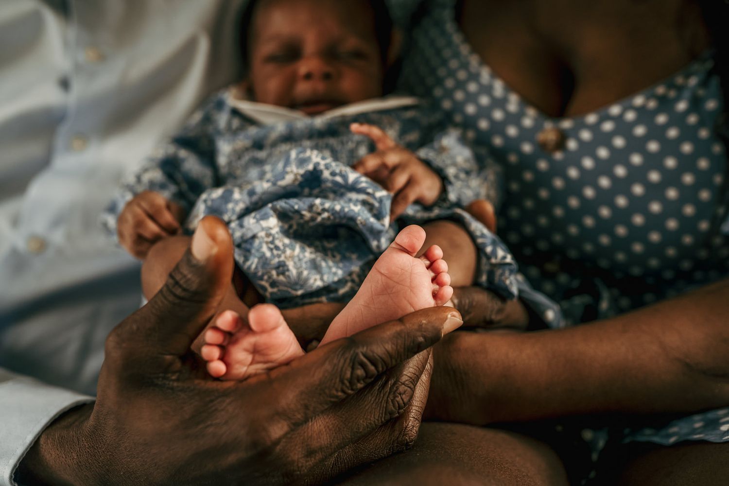 Close-up of father's hands holding his newborn baby's feet