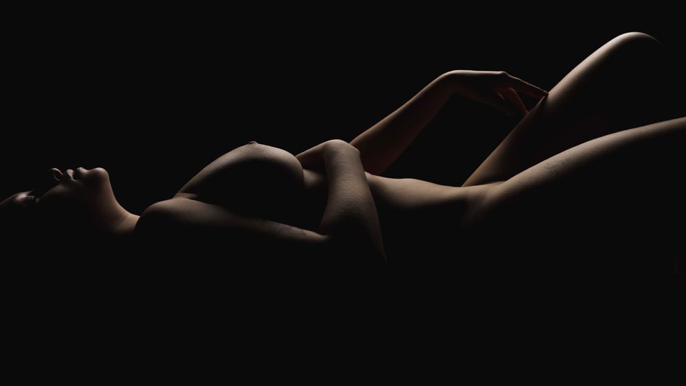 Minimalist black and white study of reclining form with gentle lighting.