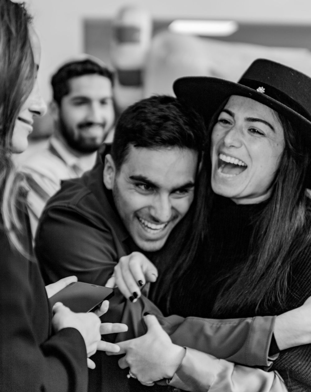 A group shares a candid moment of laughter while wearing casual attire and a black hat.