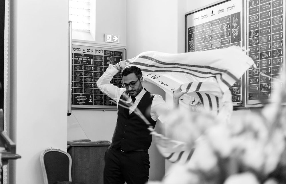 A person in formal attire dances joyfully with a white cloth during a celebration.